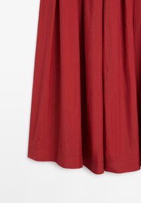 Punainen midi-hame, joka on valmistettu teksturoidusta kankaasta, varustettuna kerätyllä vyötäröllä ja helmalla, joka ulottuu juuri nilkkojen ylle, tasaisella pinnalla.