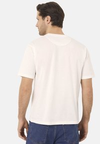 Bílá bavlněná tričko s krátkým rukávem, kulatým výstřihem a volným střihem. Hladká textura s jednoduchým designem; žádné viditelné vzory nebo akcenty.