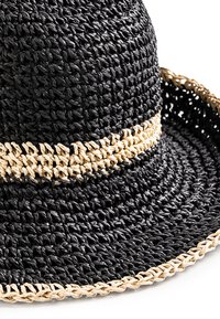 Czarny splotowy kapelusz ze słomy z szerokim rondem, ozdobiony naturalnym paskiem ze słomy owiniętym wokół, podkreślającym kontrastowe kolory i tekstury.