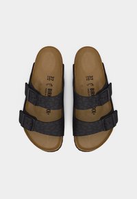 Ζευγάρι μαύρα σανδάλια Birkenstock με διπλά ρυθμιζόμενα λουριά με αγκράφες και καφέ περιμετρικά διαμορφωμένες πάτους, εμφανίζονται από πάνω σε λευκό φόντο.