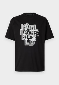 Fekete pamut póló, merész, rétegezett fehér betűtípussal, amely "KARL LAGERFELD" szöveget formázza, klasszikus kerek nyakkal és rövid ujjal.