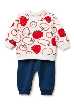 Weißes Langarmshirt für Kleinkinder mit lächelnden roten Tomatenmotiven, kombiniert mit marineblauen, fein gerippten Hosen.