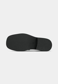 Black shoe sole with a textured finish, featuring a slightly contoured shape and a smooth, flat design. Minimal branding visible.