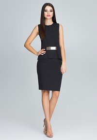 Strak zwart jurkje met mouwloze top en aansluitende rok. Voorzien van een metallic accent op de taille. Gladde textuur, knielang ontwerp.