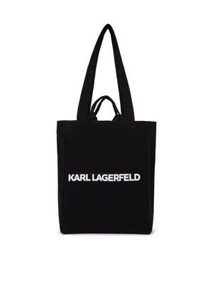 Černá taška typu tote s dlouhými a krátkými uchy, s výrazným bílým nápisem "KARL LAGERFELD" umístěným uprostřed vpředu.