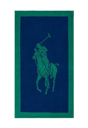 Groen en marineblauw tapijt met daarop een polospeler te paard die een opgeheven knuppel vasthoudt, omgeven door een brede groene rand.