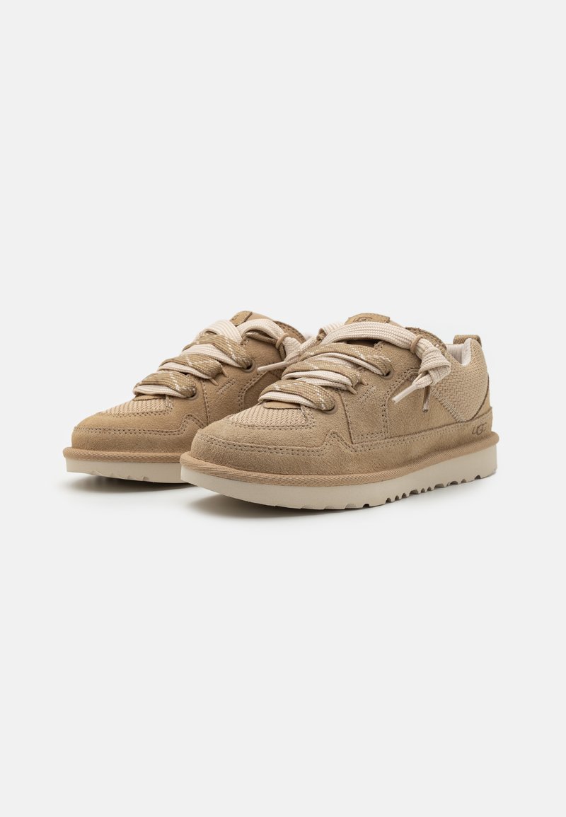 Beige Wildleder-Sneaker mit strukturierten Details, runder Zehenpartie und passenden Schnürsenkeln. Verfügt über eine hellfarbene Gummisohle mit einem gemusterten Profil.