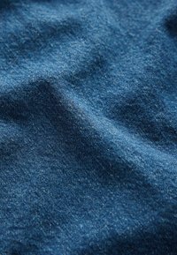 Mörkblå denimtyg med en jämn textur, som har subtila vävda mönster och små variationer i färg, vilket indikerar naturliga fibrer.