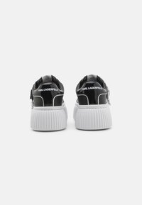Sneakers in pelle verniciata nera con suole in gomma bianche a flauto. Le caratteristiche includono un retro con marchio e dettagli in metallo argentato.