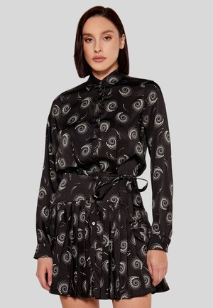 Camicia nera con motivi a spirale argentati, con bottoni sul davanti, maniche lunghe e una gonna plissettata con una cintura annodata in vita.