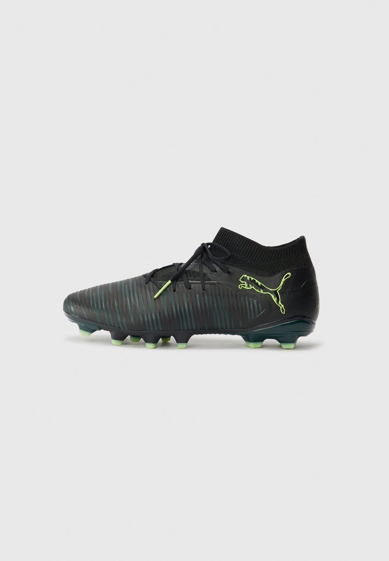 Black soccer cleats with a textured design, featuring a fitted ankle collar, green accents, and conical studs on the outsole.