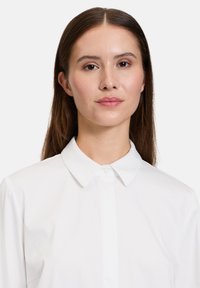 Hvid skjorte med knapper og struktureret krave, glat stof, lange ærmer og et åndbart design. Minimalistisk stil med et klassisk udseende.