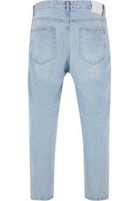 Svetlo modri denim traperice z vidnim bledečim efektom, s ravnim krojem, petimi žepi in gumbom za zapiranje na pasu.
