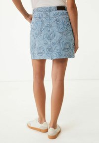 Denimová sukně světle modré barvy s bílými květinovými výšivkami, s polovičním pasem a zadními kapsami. V kombinaci s bílými teniskami.