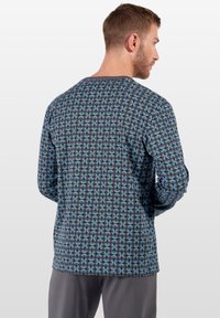 Langärmliges Hemd aus dunklem Stoff mit blauem und schwarzem Spiraldesign. Es hat einen runden Ausschnitt und eine lockere Passform.