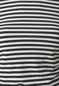 Svart og hvit stripete stoff med en ribbete tekstur, som har vekslende smale striper i et konsistent mønster gjennom hele.