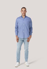 Blau-weiß karierte Hemd mit Knöpfen, lange Ärmel, kombiniert mit hellblauen Jeans und weißen Turnschuhen. Einfaches Design, lässige Passform.