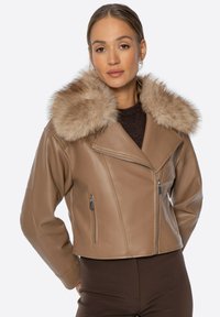 Tan leren cropped jasje met een faux fur kraag, zijzakken met ritssluiting en een reverskraag. Soepele textuur en gestroomlijnde vorm.