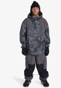 Herrsnöbordsoverall med en grå kamouflagepullover med en framficka och grå cargobyxor med svarta detaljer. Inkluderar handskar och en mössa.