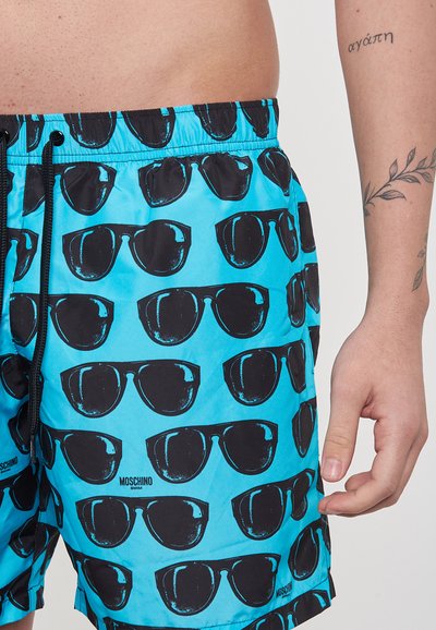 Pantaloni da bagno blu con una stampa di occhiali da sole neri ripetuta, dotati di elastico in vita con cordoncino e una texture di tessuto liscia e leggera.