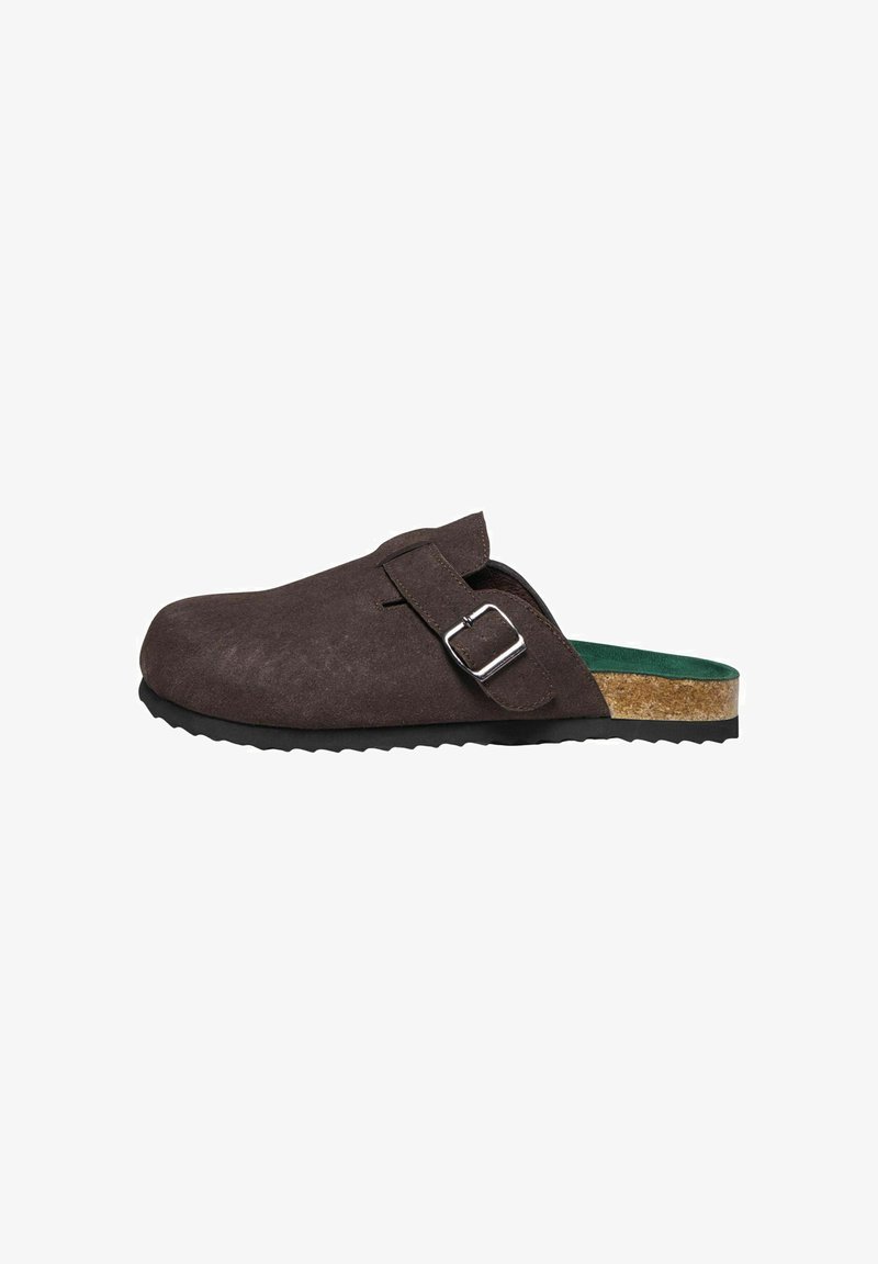 Chaussure marron en daim à enfiler avec une boucle latérale, semelle intermédiaire en liège, semelle intérieure verte et semelle extérieure en caoutchouc noir texturé, vue de côté.