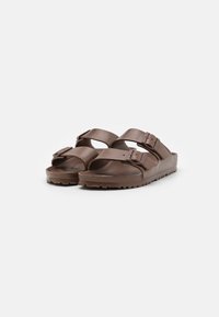 Brune plastsandaler med to justerbare remspenner, en teksturert såle og åpen tå-design. Lettere og enkle å rengjøre.