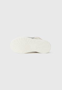 Beige suede sneaker with white rubber sole featuring star pattern and textured surface, showing underside with a design of sunburst and stars.