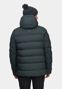 Ciemnozielona kurtka puchowa z wysokim kołnierzem oraz czapka z dzianiny w kolorze czarnym. Posiada poziomy wzór pikowania, zapięcie na napy oraz akcentowane logo z tyłu.