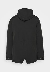 Parka noire à capuche avec une texture lisse, taille cintrée et poignets à bouton-pression. Elle présente un ourlet en demi-cercle et une boucle supérieure pour l'accrocher.