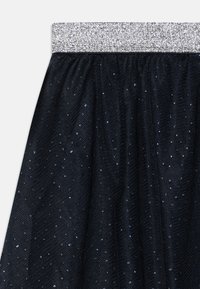 Svart tyllskjørt med en sølvglitrende midje, med spredte blanke blå og sølvføyninger i hele stoffet.