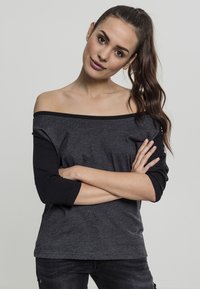 Off-shoulder topp i mørkegrått med lange svarte ermer, med løs passform og glatt tekstur, egnet for hverdagsbruk.