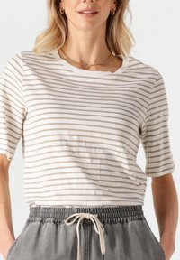 Gestreepte korte mouwen t-shirt in crème en lichtbruin, met een ronde hals en een losse pasvorm, gecombineerd met grijze joggingbroeken met een trekkenkoord.