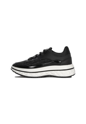 Scarpa sportiva nera con tomaia in rete e dettagli lucidi, suola intermedia spessa e testurizzata di colore bianco e suola esterna in gomma nera.