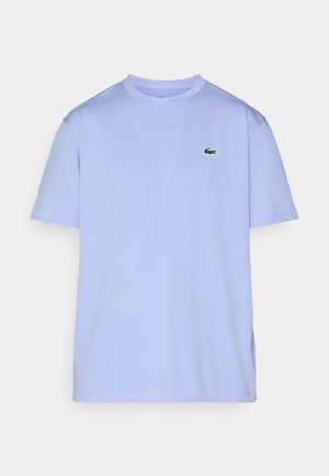 Camiseta de manga corta azul claro hecha de suave algodón. Presenta un pequeño logo de cocodrilo bordado en verde en el lado izquierdo del pecho.