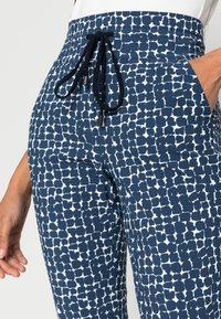 Navy and white patterned pants with an elastic waistband featuring a drawstring. Made from a soft fabric with a textured look and side pockets.