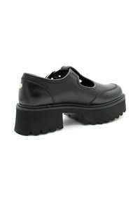 Zwarte leren schoen met uitgesneden zijdetails, dikke zwarte rubbere zool met een getande rand en een metallic accent op de hak.