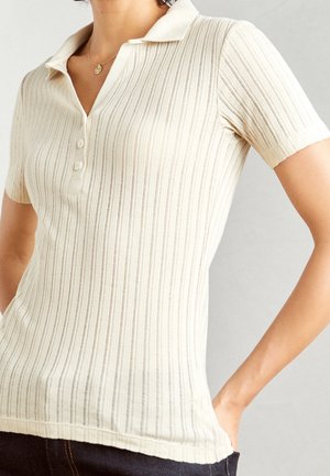 Crème-kleurige polo shirt van ribbelstof, met een kraag, korte mouwen en een drie-knoopsluiting.