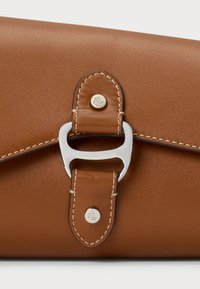 Brun lærveske med en jevn tekstur, med en sølvfarget metallklips og kontrasterende hvite sømmer. Akkompanjeres av merket hardvare.