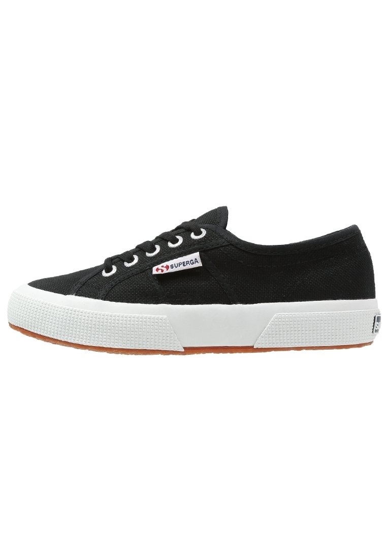 Zapatillas de lona negras con suela de goma blanca, punta redonda y cierre de cordones. Cuenta con una suela texturizada y un parche con el logo en el lateral.