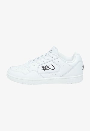 Valged sneakerid sileda nahk välispinnaga, aukudega detailid varbapooles, mustade logo aktsentidega ja kummist tallaga.