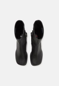Black leather ankle boots with a sleek design, rounded toe, and side zipper. Smooth texture and minimalistic silhouette.