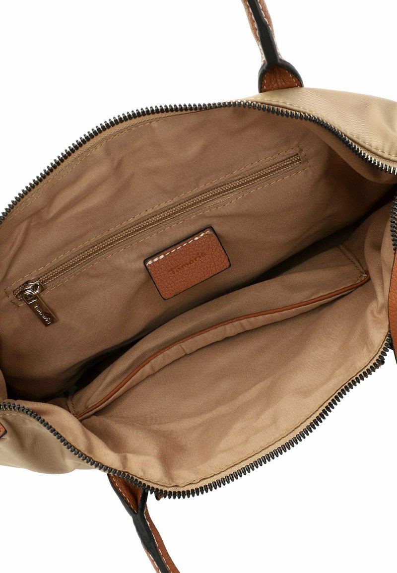 Interior de bolso color beige con una textura suave, que cuenta con un bolsillo con cremallera y una etiqueta de cuero marrón. Accentuado con un borde de cremallera oscura.