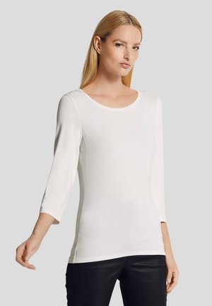 Witte driekwartmouwen top van een gladde, lichte stof met een ronde hals en een aansluitende silhouet. Naadloos ontwerp, minimalistische accenten.