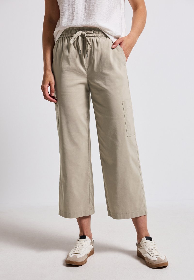 Lichtbeige, wijde broek met een verstelbare koordsluiting in de taille en zijzakken. Gemaakt van een zachte, gestructureerde stof. Casual ontwerp.