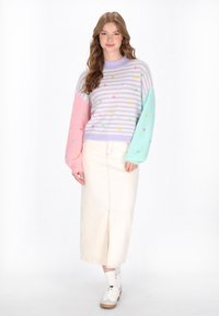 Maglione lavorato a maglia con corpo a strisce lavanda e rosa, maniche azzurre e ricami floreali; abbinato a una gonna crema e sneakers bianche.