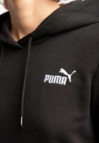 Felpa nera con cappuccio in morbido tessuto, caratterizzata da un logo "PUMA" ricamato in bianco e da una silhouette di puma sul petto, con lacci regolabili nel cappuccio.