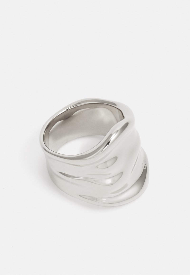 Anello ondulato in argento realizzato in metallo lucido, caratterizzato da una superficie liscia e da un design allungato e irregolare. Nessun motivo o accento visibile.