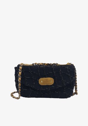 Sac d'épaule en tissu noir texturé avec une bandoulière en chaîne en cuir marron clair et une étiquette en cuir marron clair embossée de "mila louise PARIS" sur le devant.