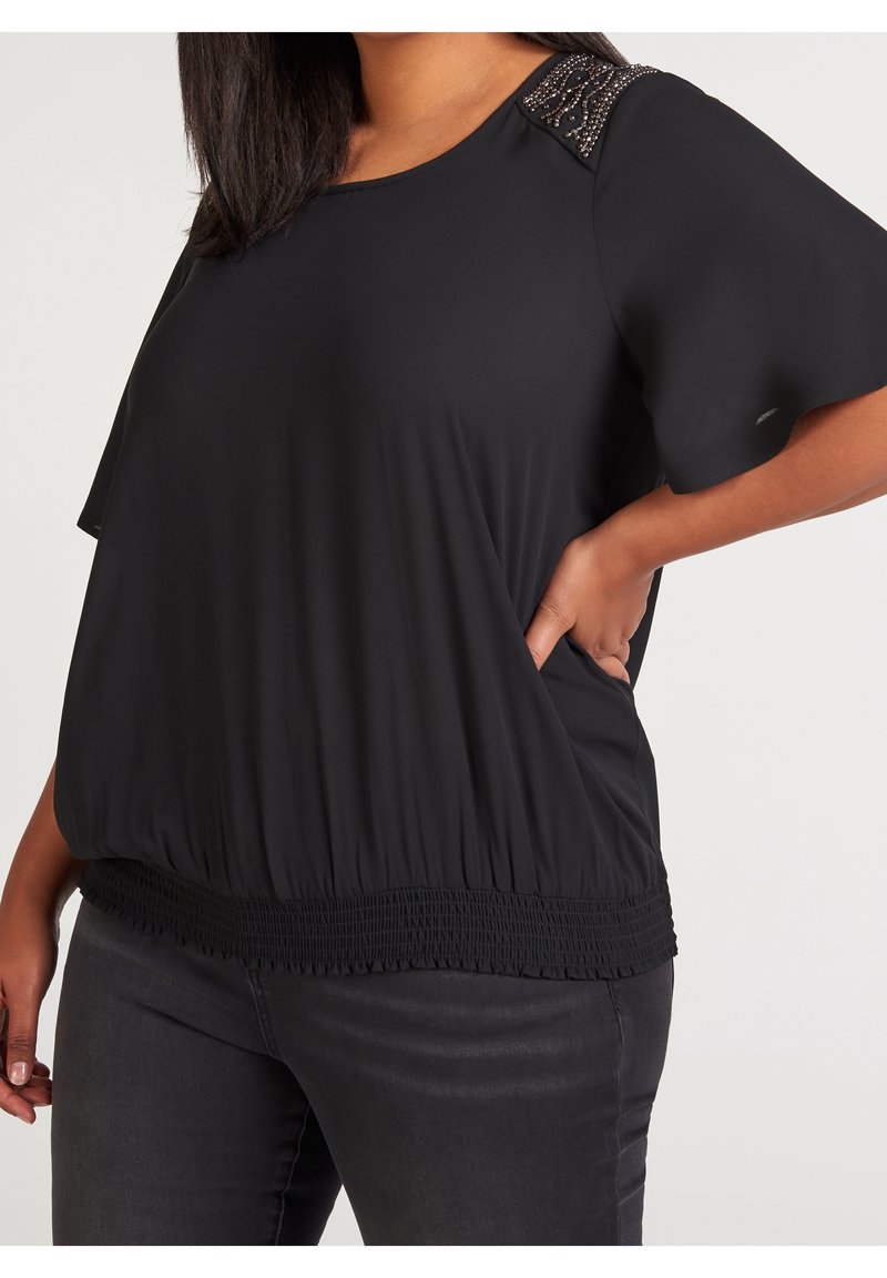 Svart kortärmad topp med lös passform, smockad nederkant och dekorativ pärlbrodering på axlarna. Mjuk, lätt tyg.