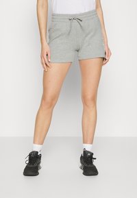 Pantalones cortos de mezcla de algodón grises con cinturilla elástica y cordón, con un estampado lateral. Combinados con zapatos deportivos negros y calcetines blancos.
